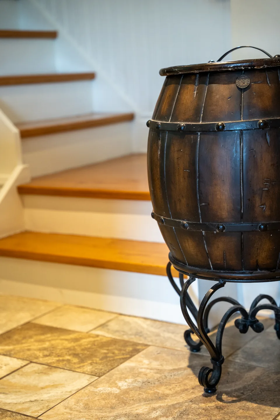 Timber staircase and a wrought-iron-strapped barrel table.