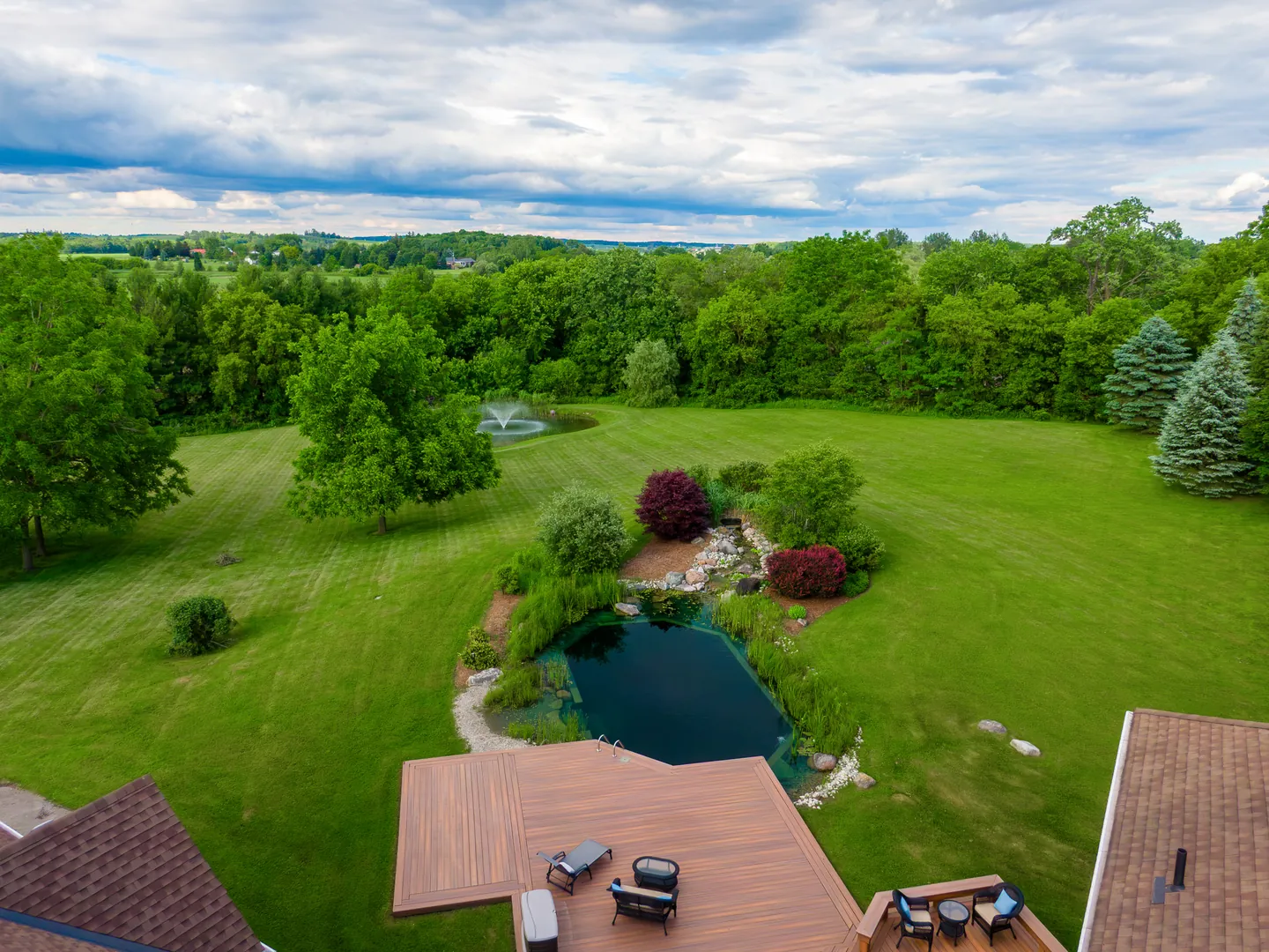 Aerial view of a natural pool, deck and lawn