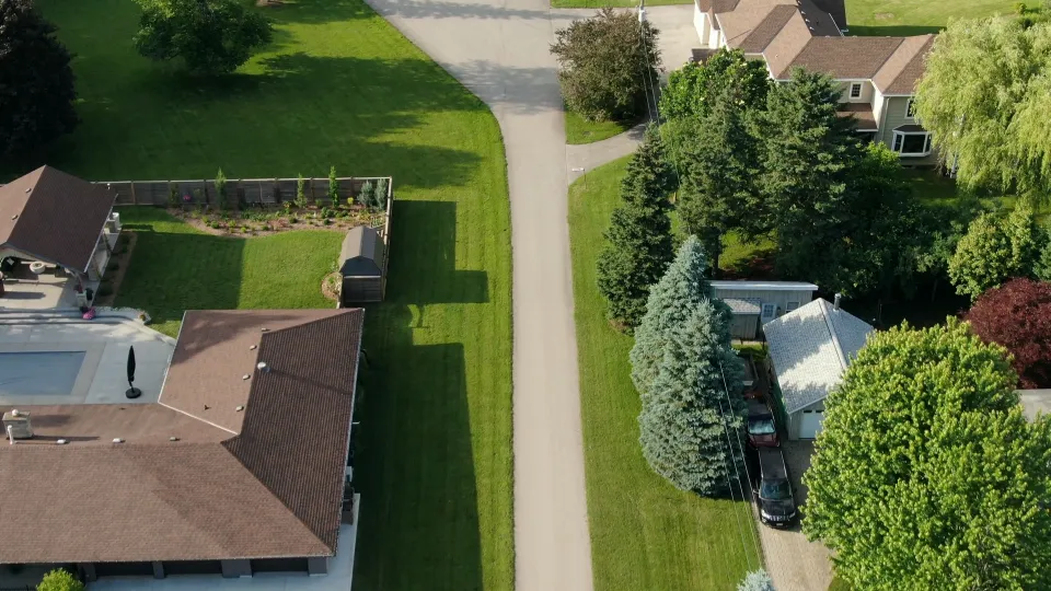 Aerial view along the street toward the property, with neighboring rooftops beyond.